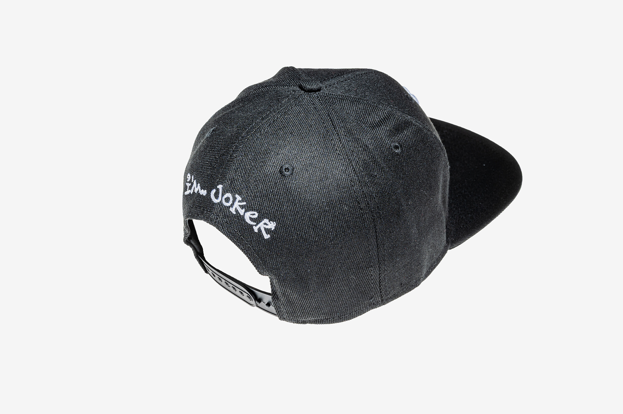 Černá snapback kšiltovka I'M..JoKeR s bílou 3D výšivkou čepičky 2 Zadní strana černé snapback kšiltovky I'M..JoKeR s bílou výšivkou a zapínáním.